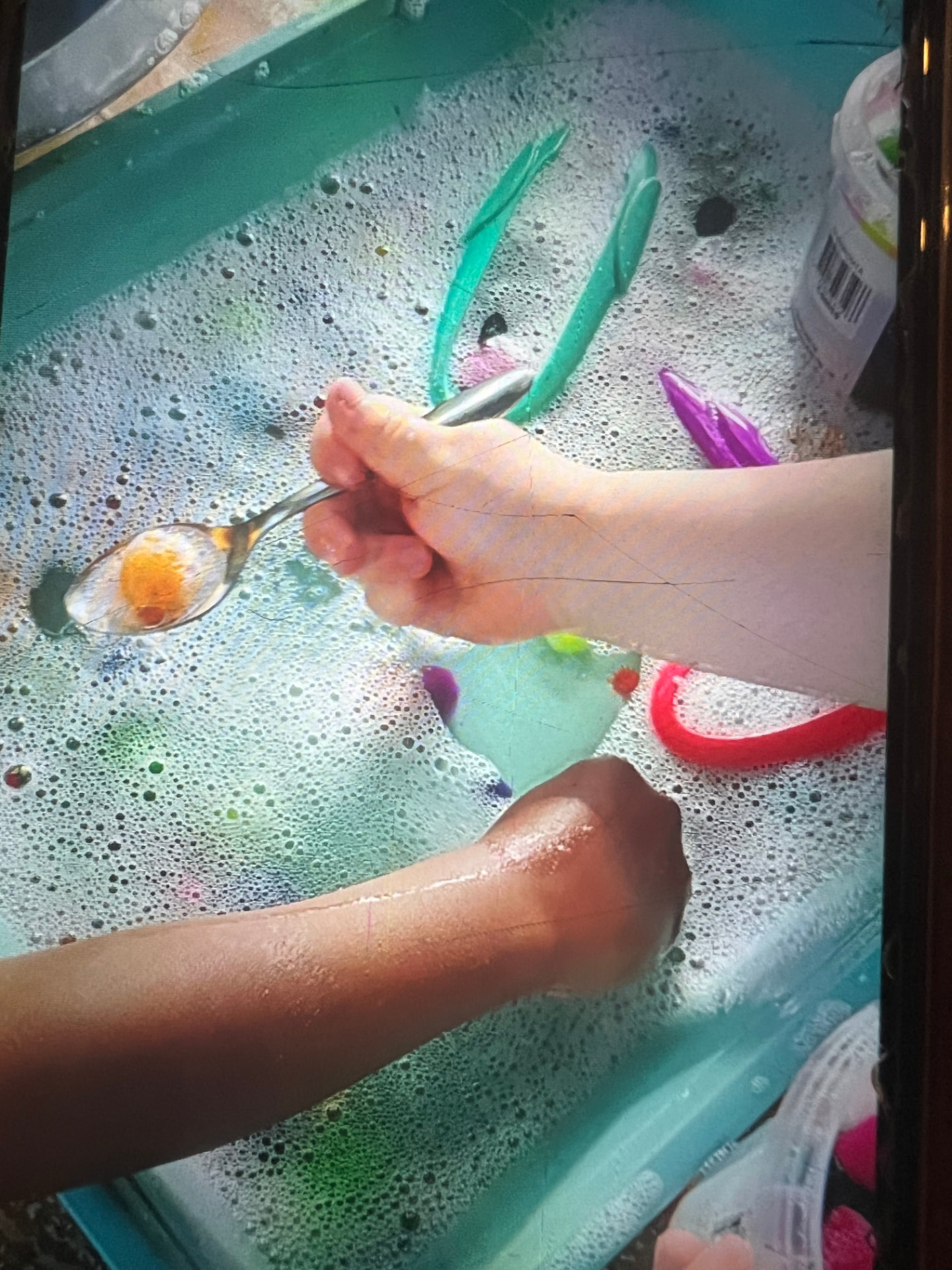 Two children mixing colour with a spoon in foam