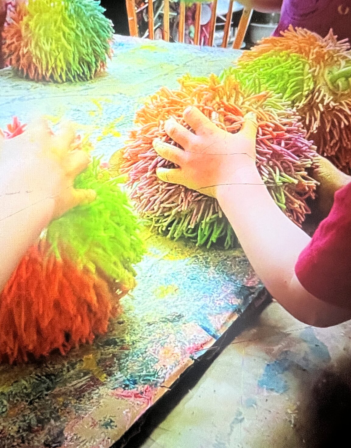 Children pressing brightly coloured textured balls onto a painted table