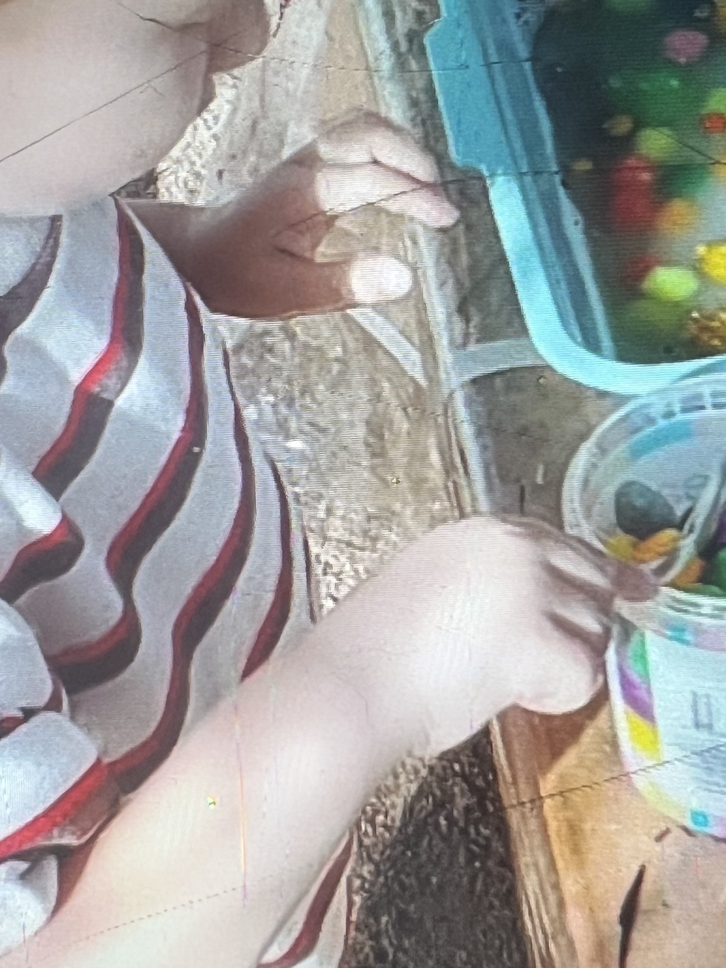 Child reaching into a tub of colourful materials